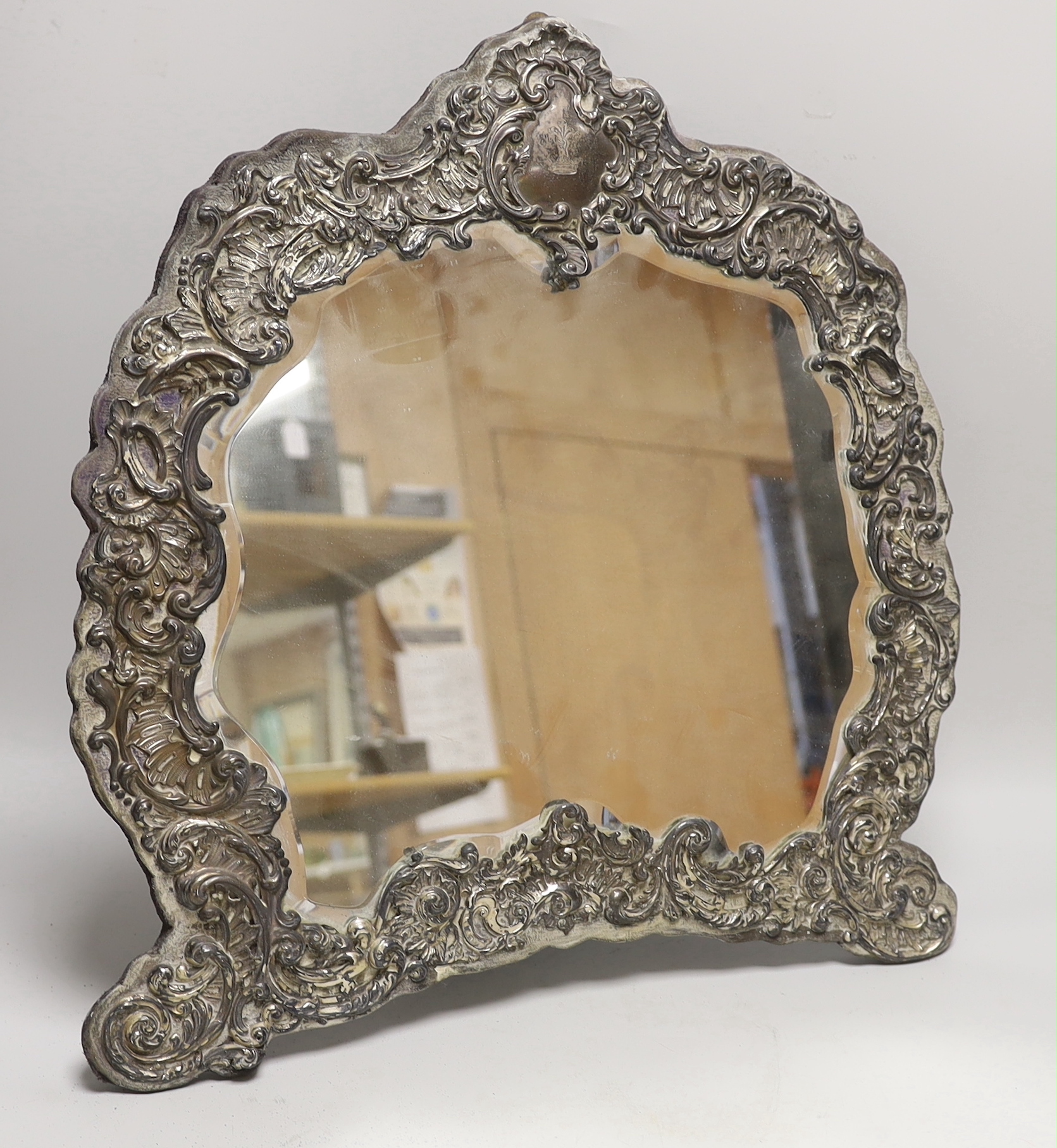 An Edwardian silver mounted cartouche shaped easel mirror, Henry Matthews, Chester, 1903, height 46cm.